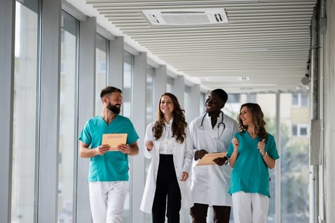 Healthcare professionals from various backgrounds smiling, walking, and collaborating in a modern hospital hallway