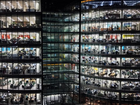 Fragment of the glass facade of a modern corporate building at night. Modern glass office in city. Big glowing windows.