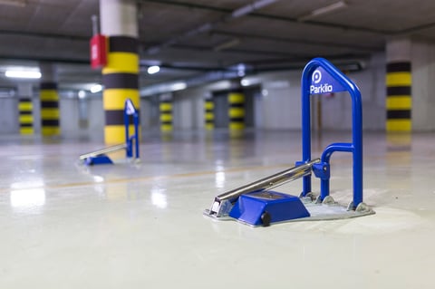 Blue parking bollards in an empty underground garage with yellow and black striped pillars visible in the background