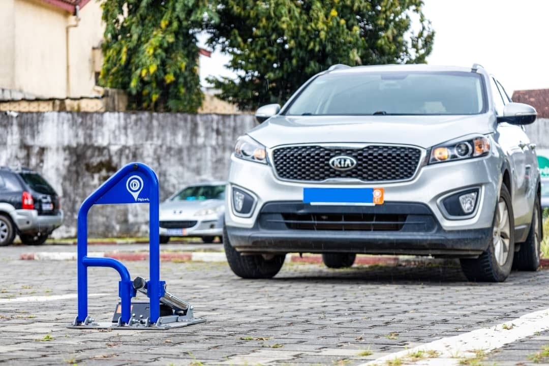 White Kia SUV parked in a lot with a blue electric vehicle charging station in the foreground